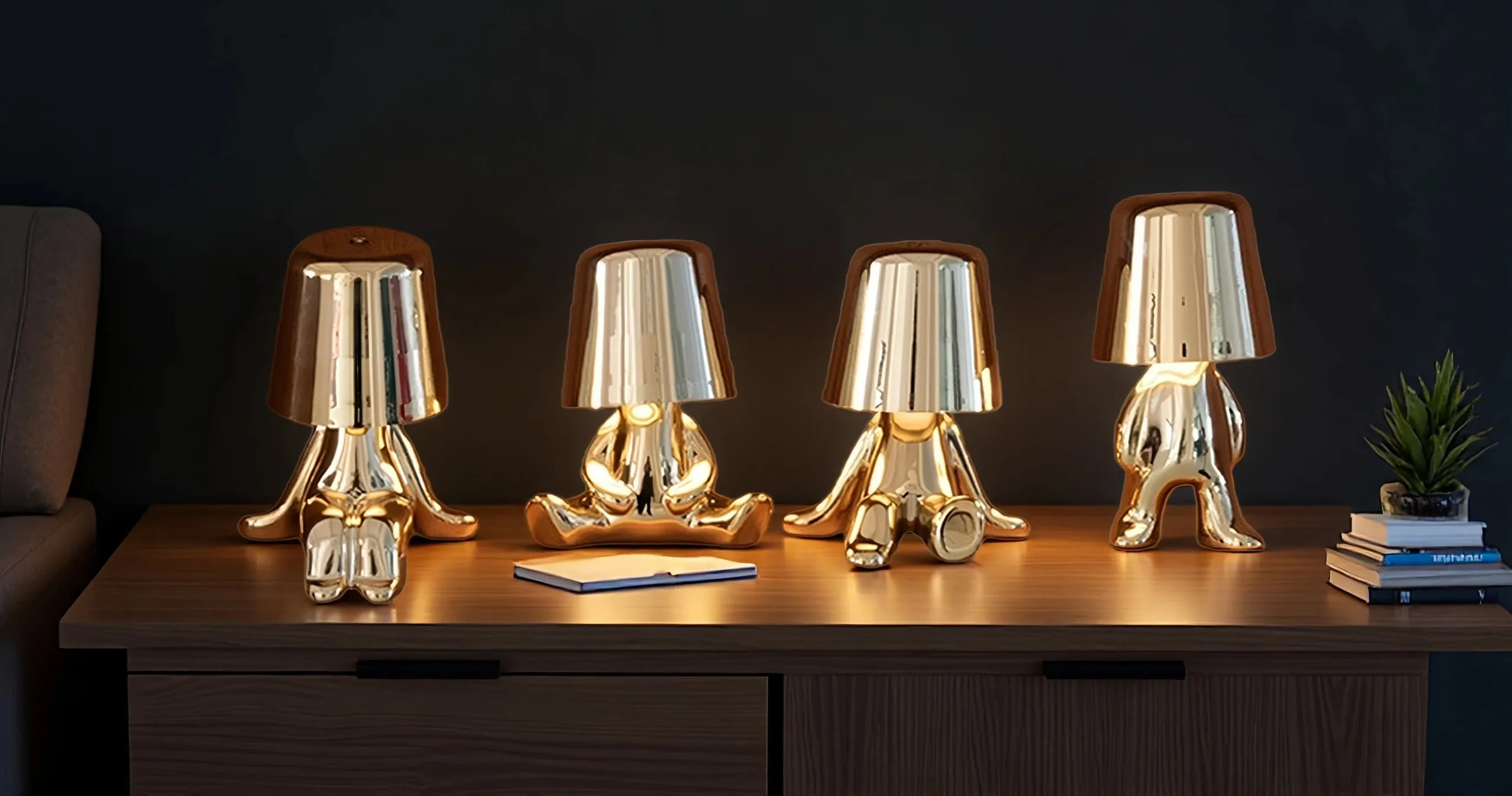 Three golden thinker statue touch table lamps sitting and standing on books like Les Misérables